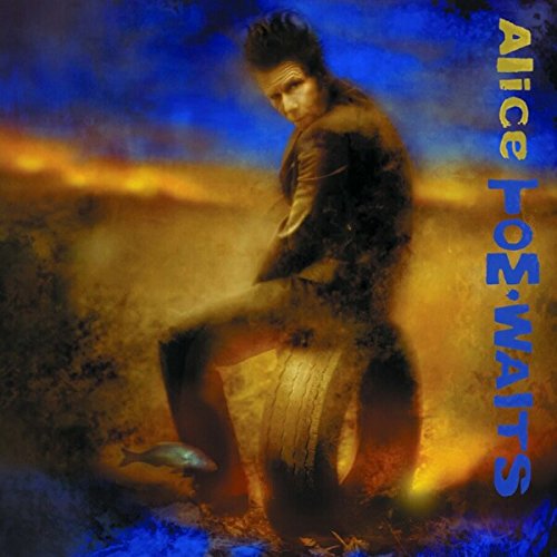 Tom Waits sitting on a tire in a hazy, dark blue and orange landscape.