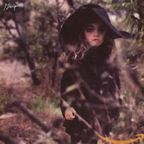 Woman in a wide-brimmed hat in a blurry, wooded landscape.