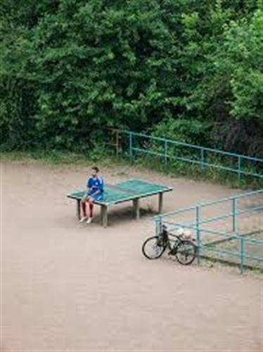 A white book cover with a photo of a person sitting alone at an outdoor ping pong table.