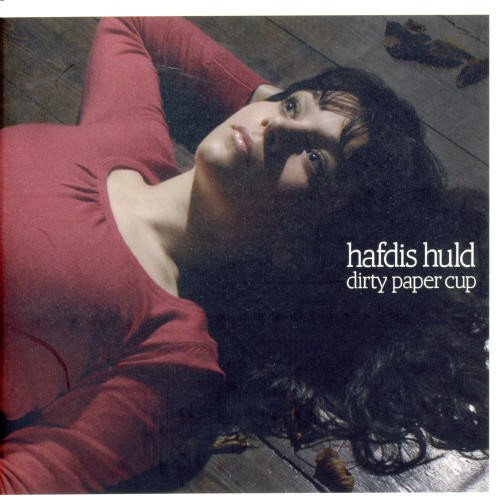 "Album cover featuring a woman lying on a wooden floor with autumn leaves."