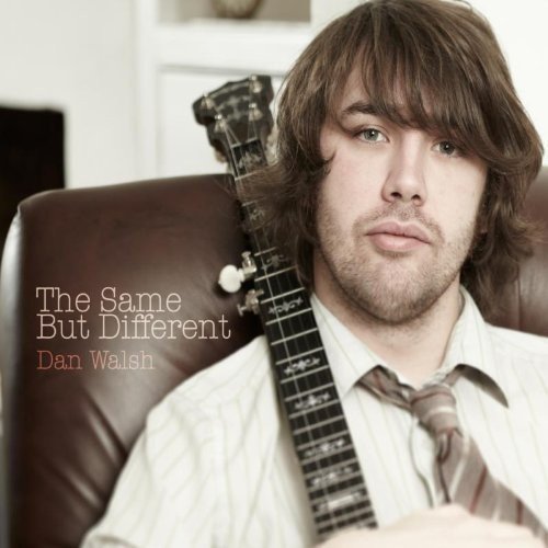 Man with brown hair holding a guitar, wearing a white shirt and tie.