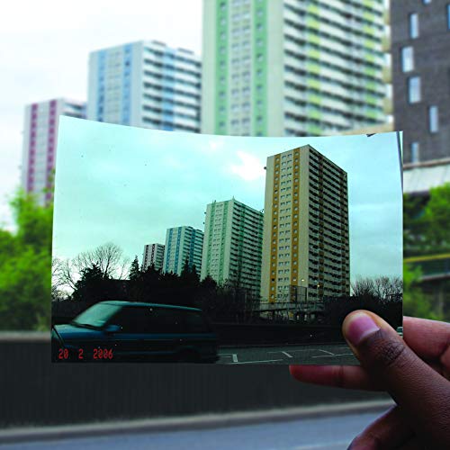 Vintage photo of high-rise buildings held by a hand, dated 2002.