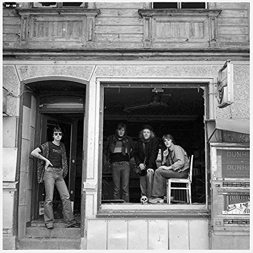 Black and white photo of four people standing in a doorway.