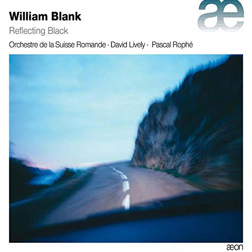 "Album cover with a blurry road and rocky cliffside under a blue sky."