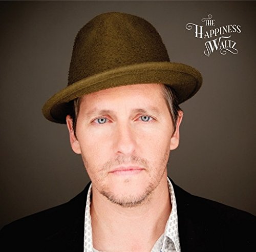 Man in a brown hat and black jacket, album cover "The Happiness Waltz".