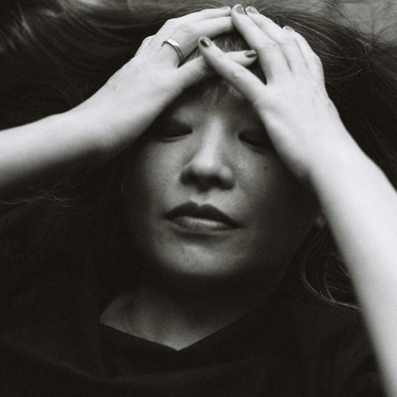 Black and white portrait of a woman with hands framing her face.