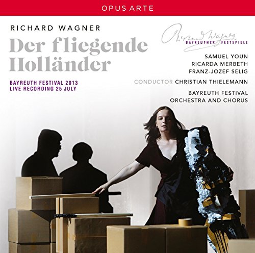 "Album cover with a woman standing among cardboard boxes, two silhouetted men in background."
