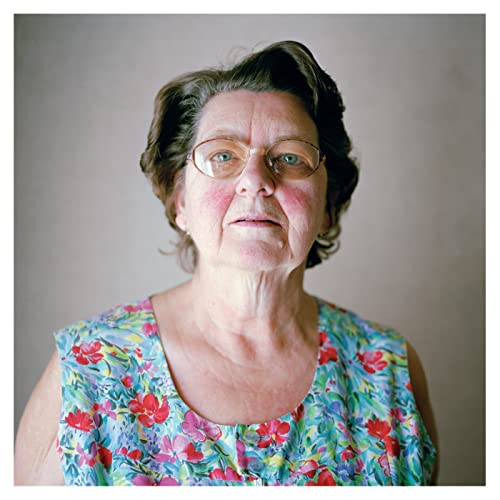 Portrait of an older woman with glasses, wearing a floral top.