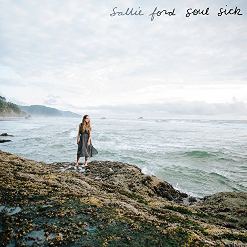 "Album cover: A woman stands on a rocky shore, ocean behind her."