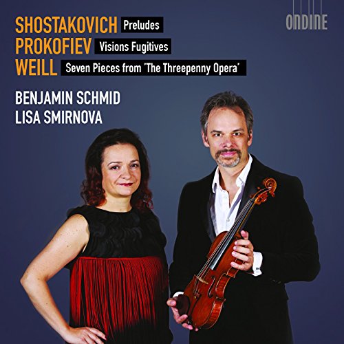 A man holding a violin stands beside a woman against a dark background.