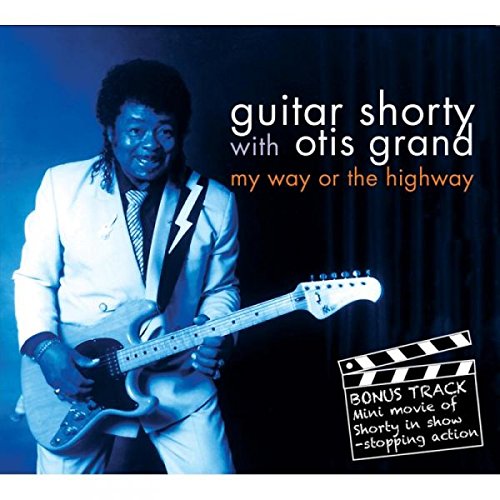 "CD cover featuring a man in a white suit playing an electric guitar."