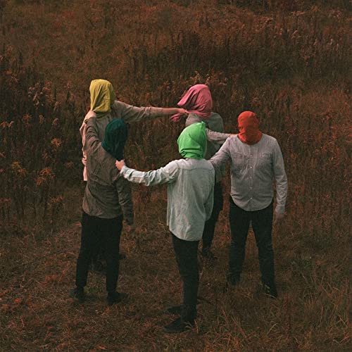 Four people with colorful fabric hoods over their heads standing in a field.
