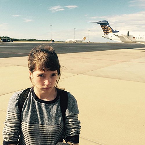 Woman with bangs and striped sweater, airport runway in background.