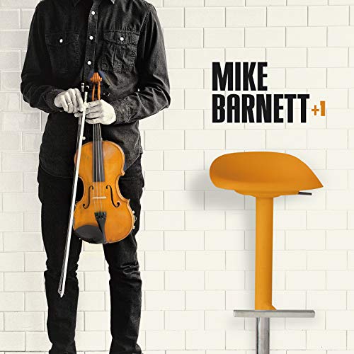 Man in black shirt and jeans holding violin bow and instrument beside orange stool.