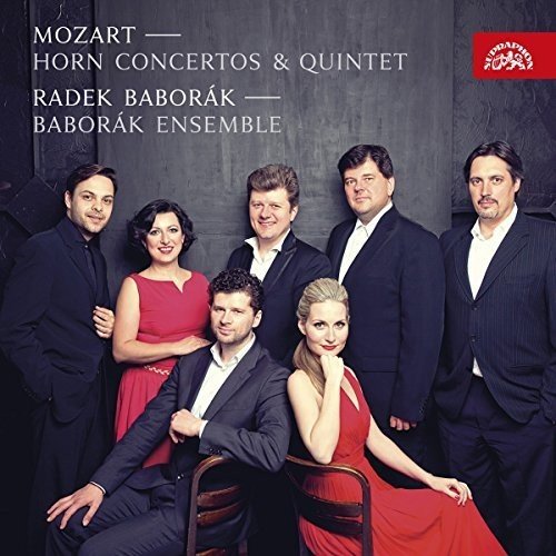 "CD cover featuring seven musicians in formal attire, with text and a red logo."