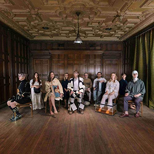 "Group of 10 people seated in a circle in an ornate, wood-paneled room."