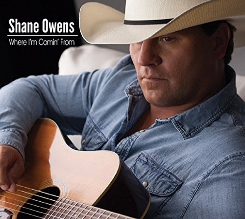 Man wearing a white cowboy hat and denim shirt, holding an acoustic guitar.