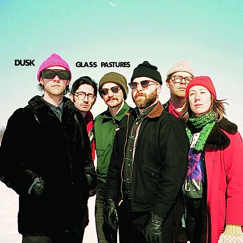 Six people in winter hats and coats stand in a field.