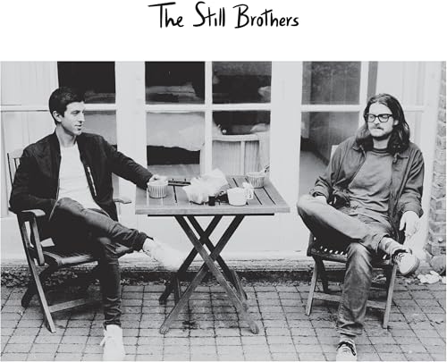 Black and white photo of two men seated at a table outdoors.