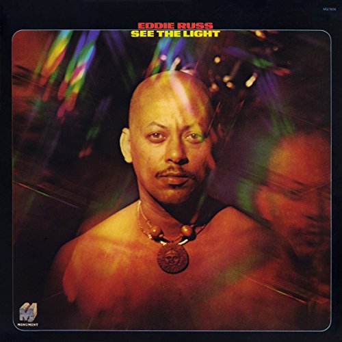 Vinyl album cover featuring a man with a pendant necklace, surrounded by colorful light effects.