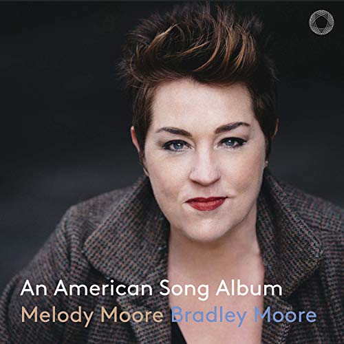 "Album cover featuring a woman with short brown hair, wearing a gray jacket."