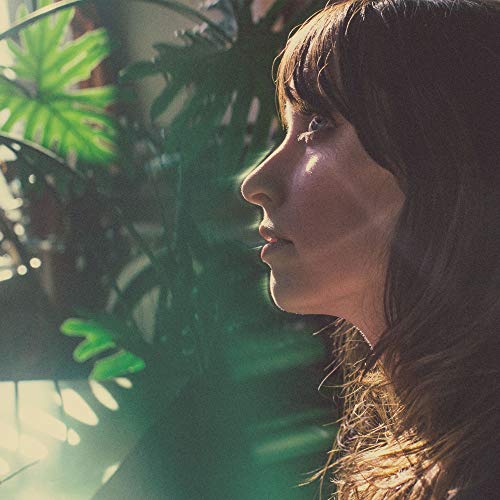 "Profile of a woman with brown hair surrounded by green plants."