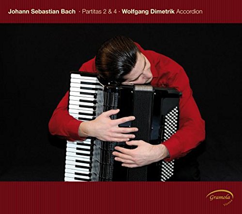 Man in red shirt playing accordion, head bowed, against a dark background.
