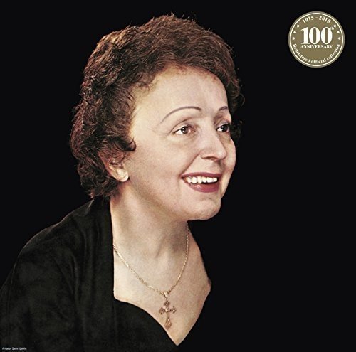 Portrait of Edith Piaf wearing a cross necklace against a black background.