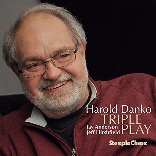 "Album cover featuring a man with gray hair and glasses, wearing a red jacket."