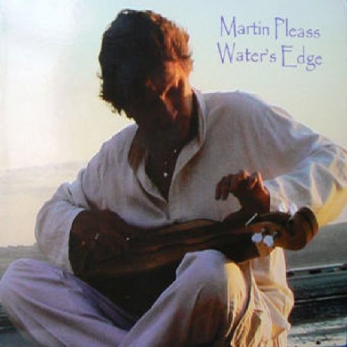"Album cover: man playing a stringed instrument, sitting outdoors at sunset."