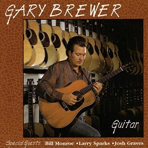 Gary Brewer with a guitar, surrounded by many other guitars.