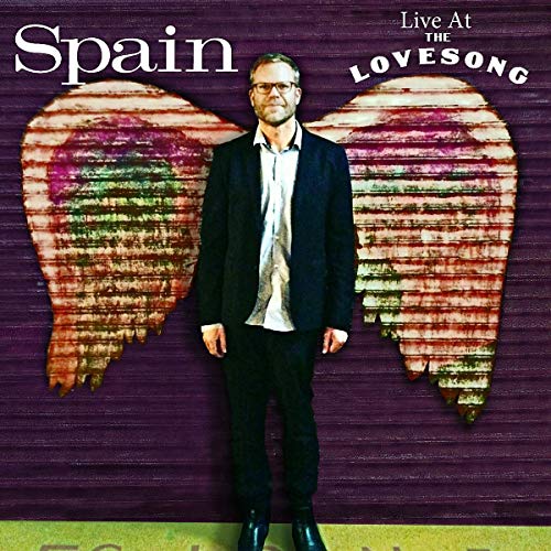 "Album cover with a man in a suit standing in front of a heart-shaped background."