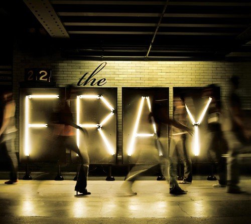 "Album cover with 'the FRAY' in large, lit-up letters on a brick wall."