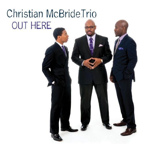 "Album cover with three men in suits standing and conversing, plain white background."