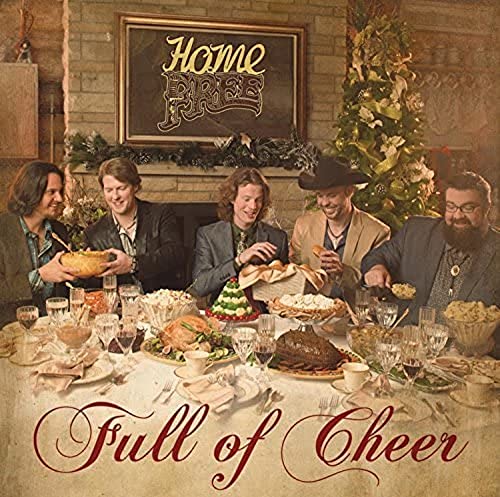 Five men around a festive holiday dinner table with a Christmas tree.