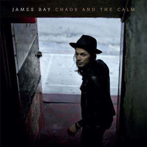 "Album cover featuring a person in black clothing and hat in a doorway."