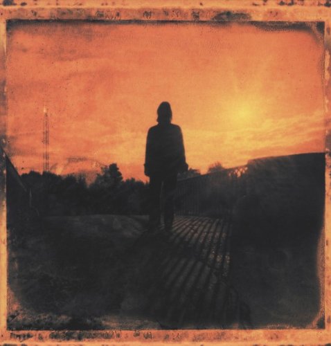 "Album cover with a person walking on a wooden bridge at sunset."