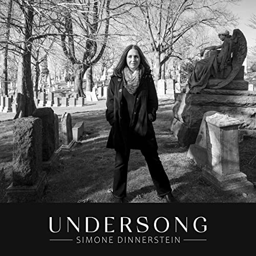 Simone Dinnerstein stands in a cemetery with a statue in the background.