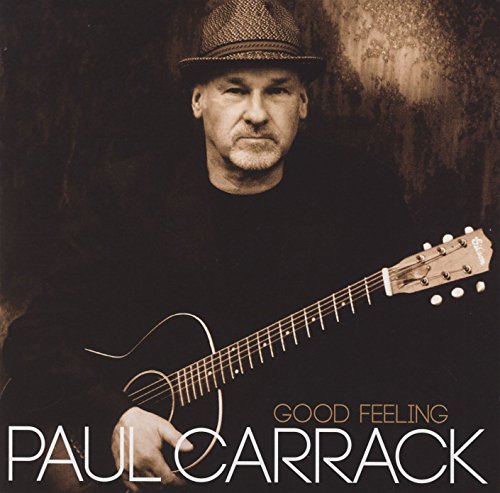 Paul Carrack holding a guitar, wearing a fedora, on a textured background.