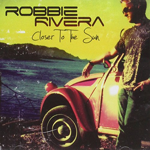 "Album cover with a man standing beside a red vintage car near water."