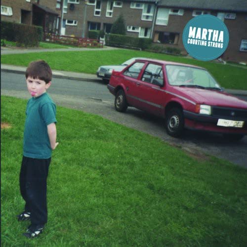 CD cover: boy standing near a red car on a street.