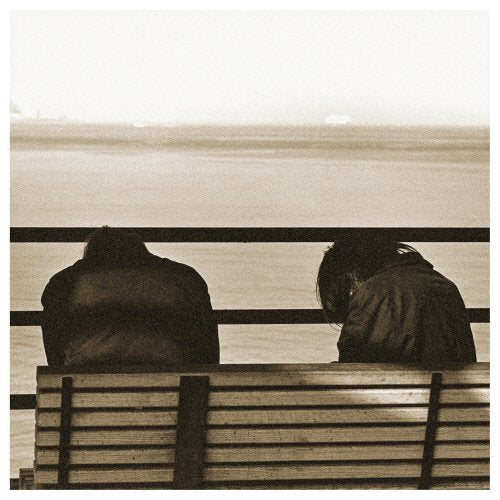 Two figures seen from behind, looking out over water.