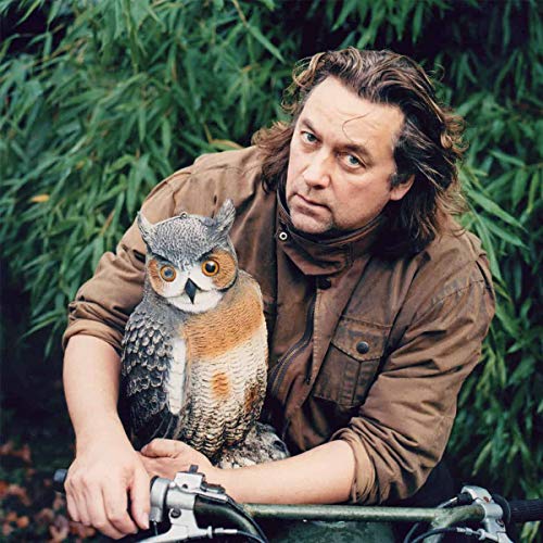 Jackie Leven with a large owl perched on his arm, outdoors.