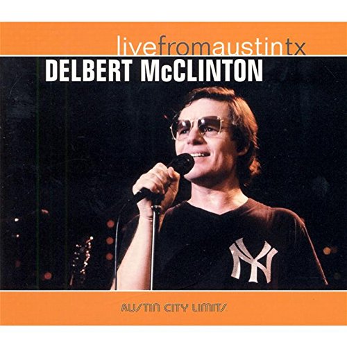 Delbert McClinton singing into a microphone, wearing sunglasses and a black New York t-shirt.
