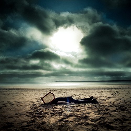The alt text for the image is: "Vinyl record album cover with a person lying on a beach."