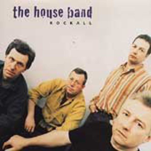 The image is an album cover for "The House Band - Rockall". * The cover features a photograph of four men. * The men are positioned in a relaxed manner, with one man in the foreground and three others behind him. * The man in the foreground is wearing a black shirt and has short hair. * The background of the image is a plain white or light-colored wall. * The title of the album, "The House Band - Rockall", is written