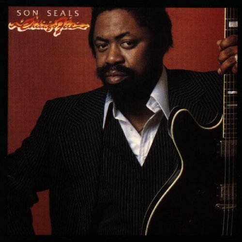 Album cover featuring a man in a suit holding a guitar against a red background.
