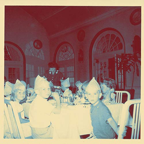 A faded, blue-toned photograph of children wearing party hats at a dining table.
