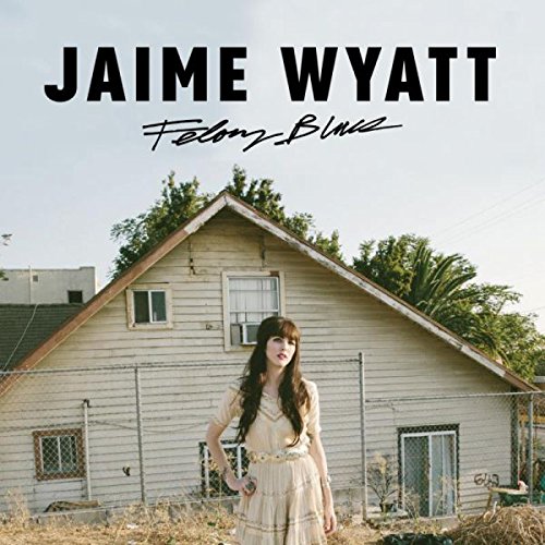 "Album cover featuring Jaime Wyatt standing in front of a weathered house."