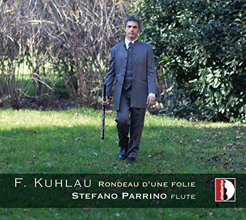 Man in suit holding a flute in a grassy park.